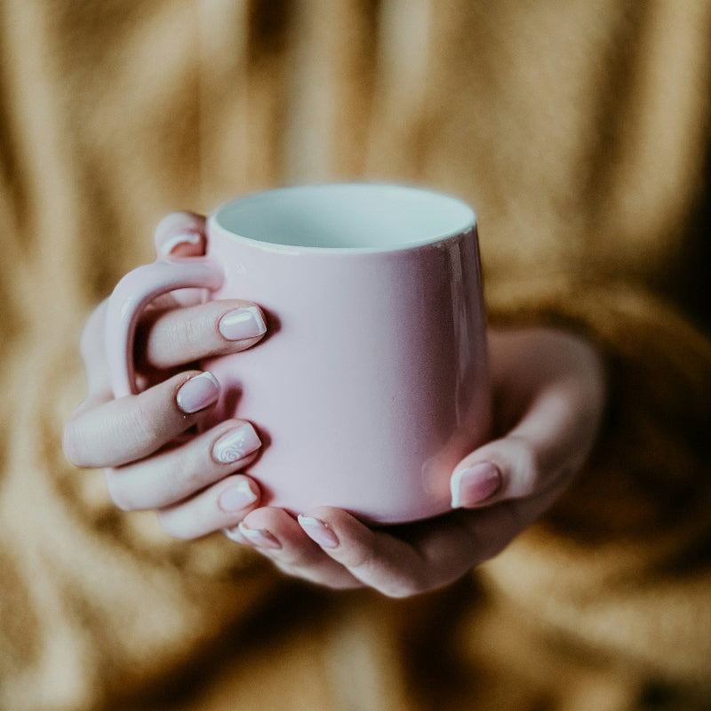 Person holding a pink mug with a blurred background