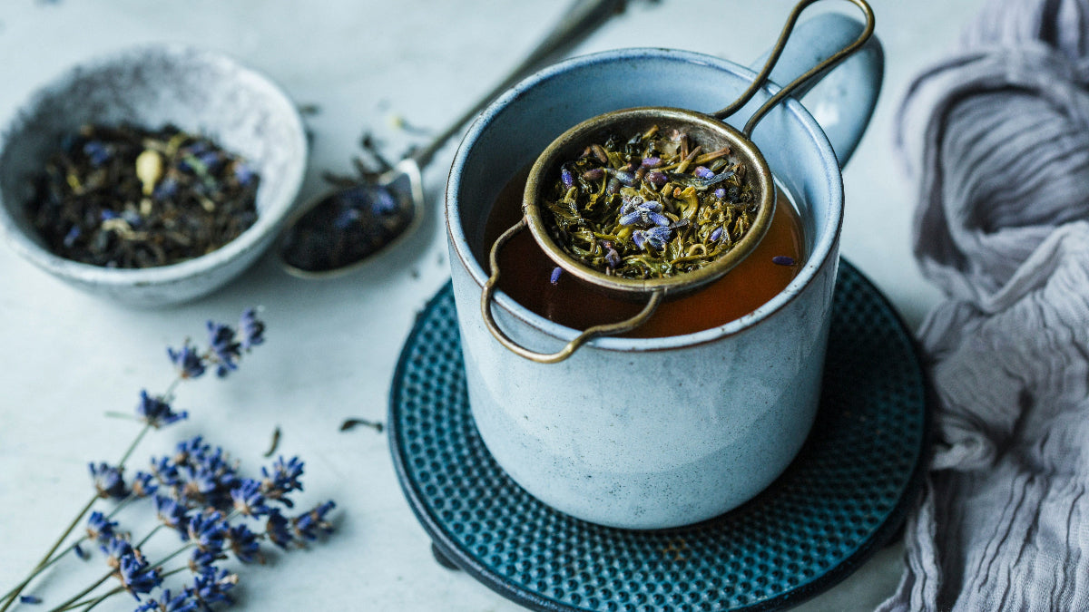 Tea cup with lavender flowers and a strainer on a textured surface