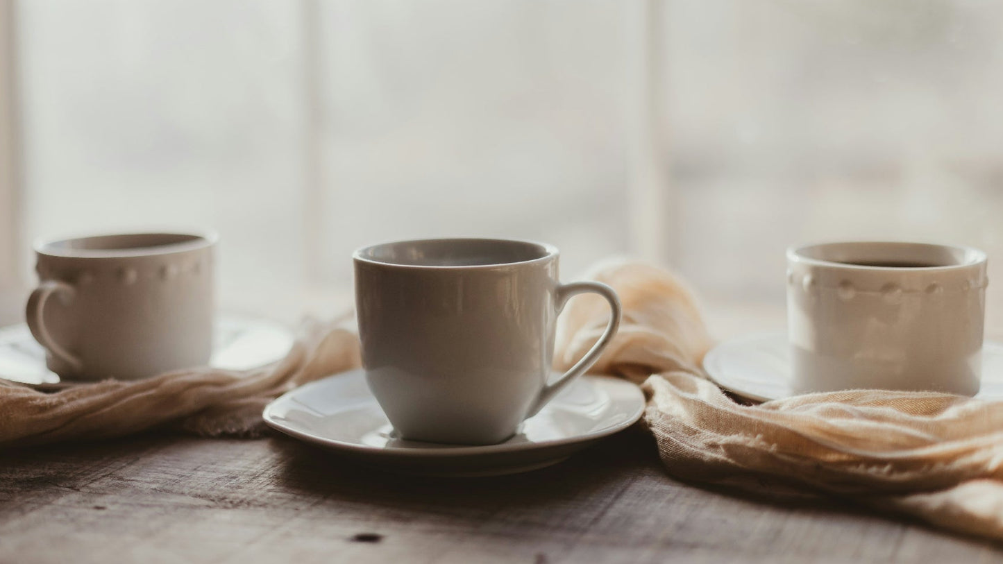 Three ceramic tea cups on a wooden table with a soft focus background