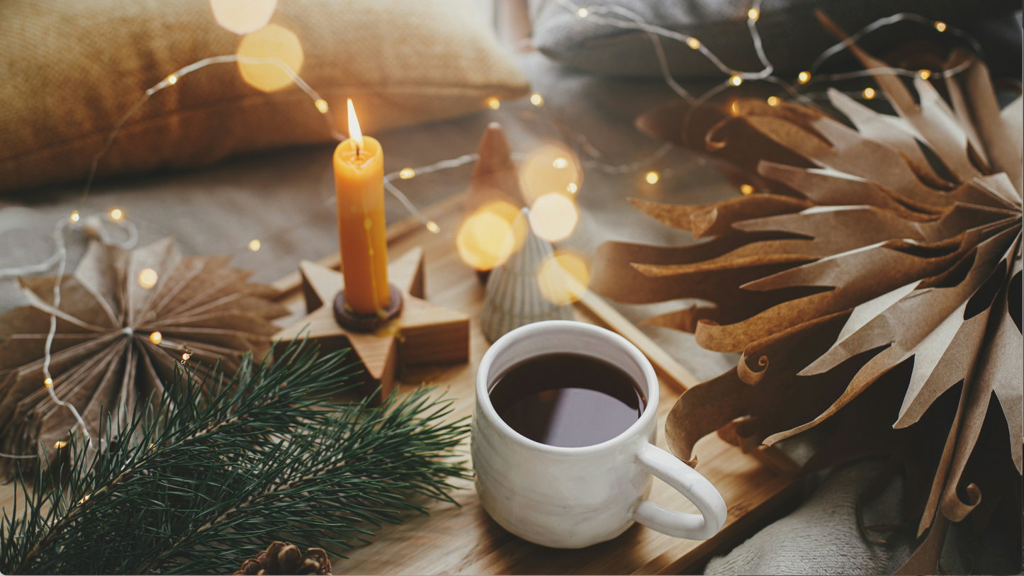 Cup of coffee with a lit candle and decorative lights on a cozy surface