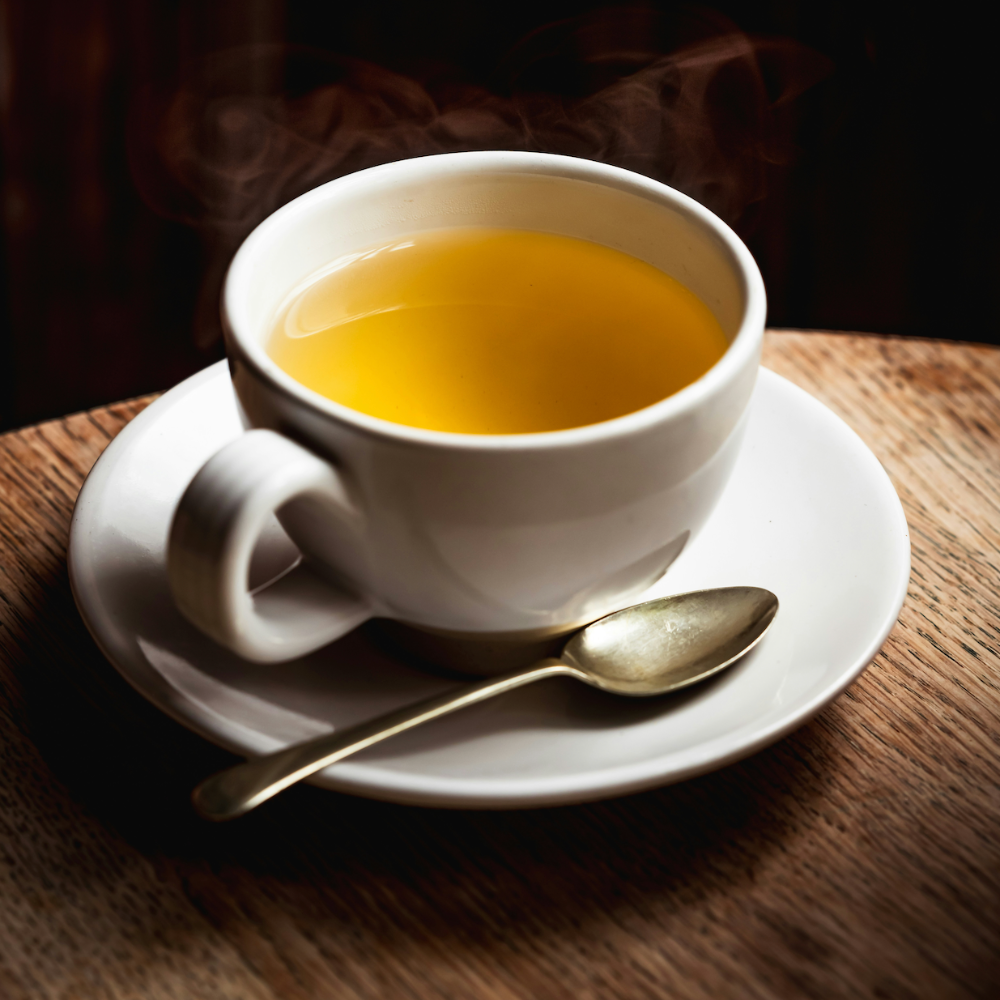 White cup of tea with a spoon on a wooden table