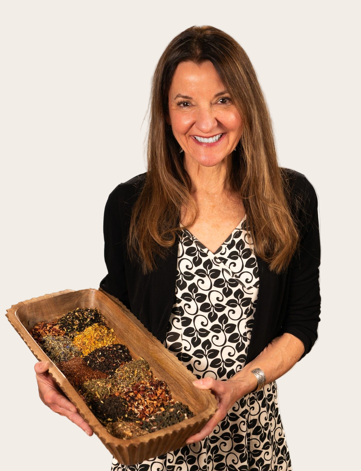 Woman holding a wooden tray with various seeds or grains against a white background