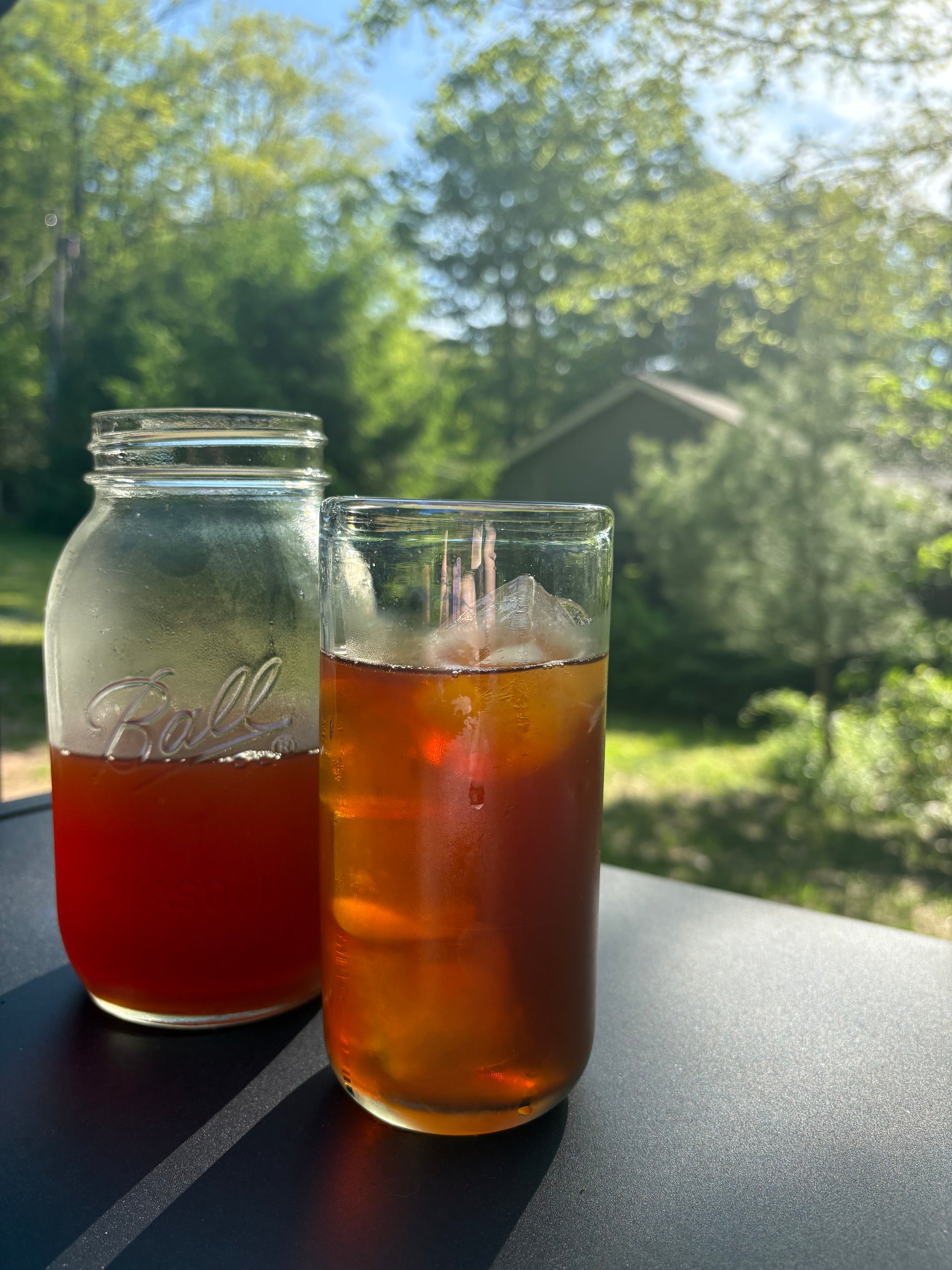 A crisp video of refreshing, amber-colored iced tea being poured into a chilled glass filled with ice cubes and fresh citrus slices, under bright summer sunlight.