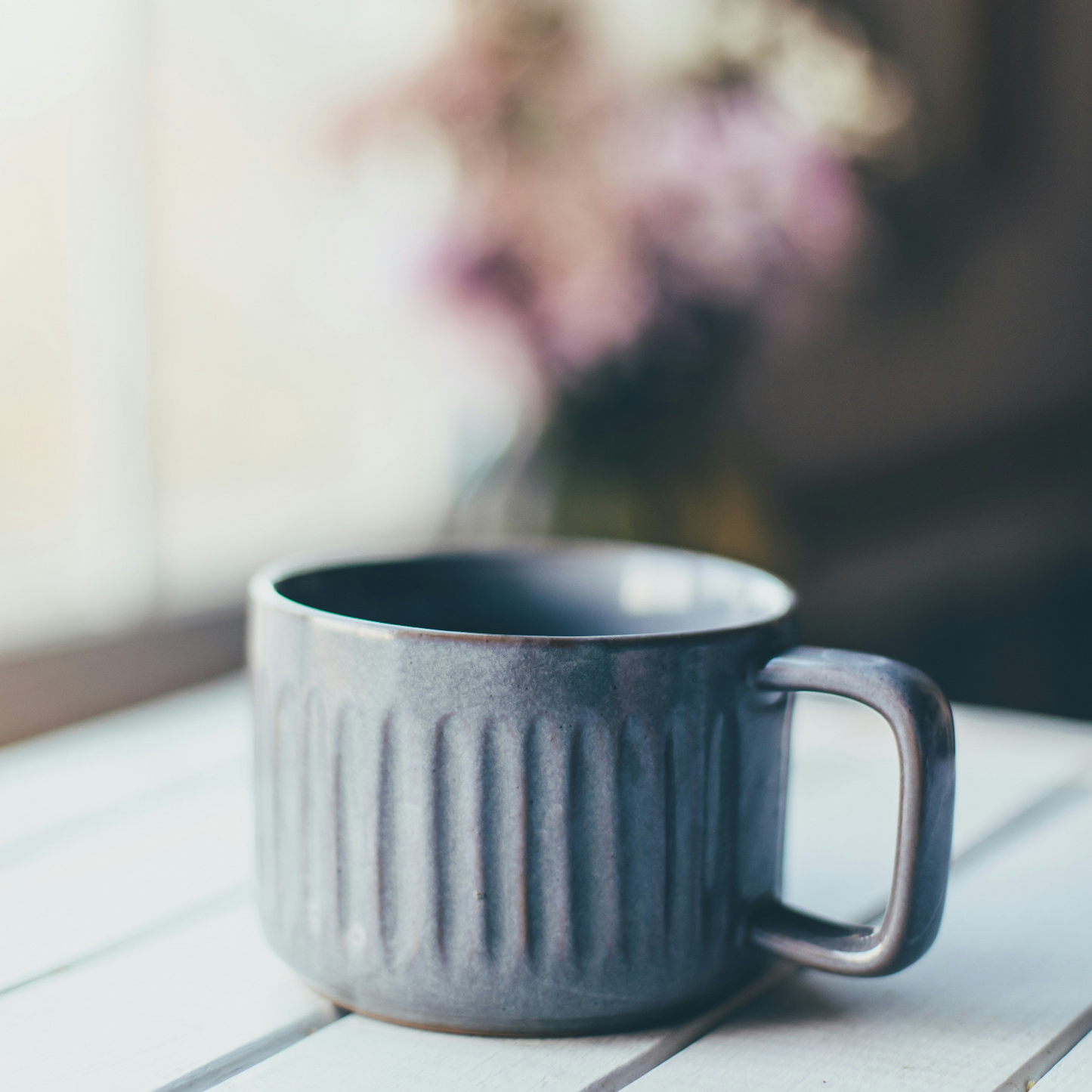 Gray ceramic mug on a white surface with a blurred background