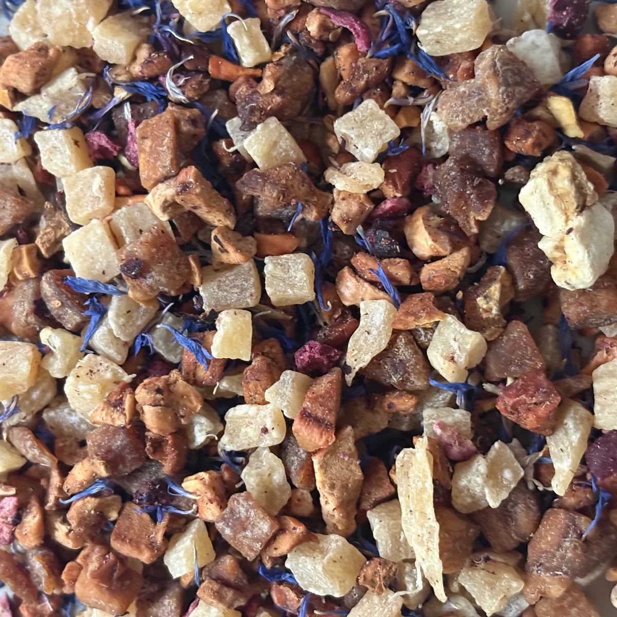 Teadaytea Banana Daiquiri premium loose-leaf herbal tea blend featuring dried banana and pineapple pieces mixed with dark black currants, tart cranberries, and vibrant blue cornflower petals.