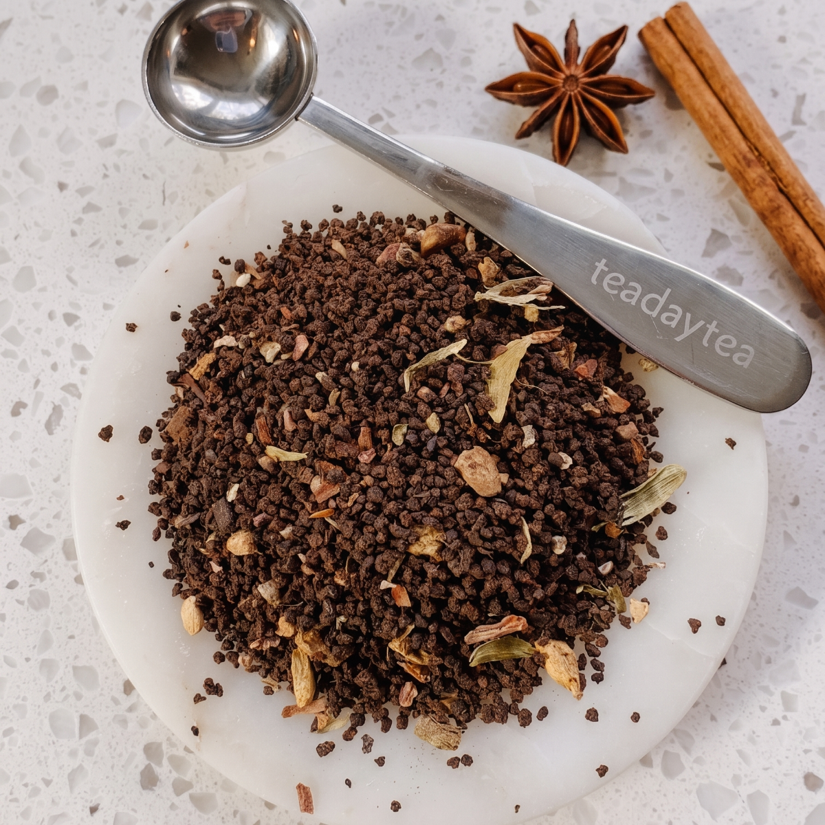 Tea leaves on a marble surface with a spoon labeled 'teadaytea'.