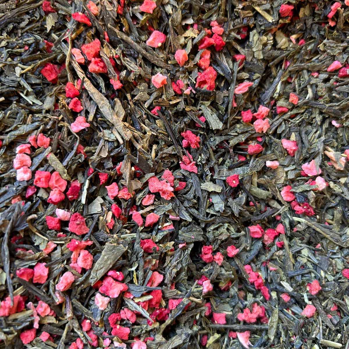 Close up of Strawberry Ice-Pop premium organic loose-leaf green tea blend featuring vibrant green tea leaves mixed with bright dried apple and juicy strawberry pieces.