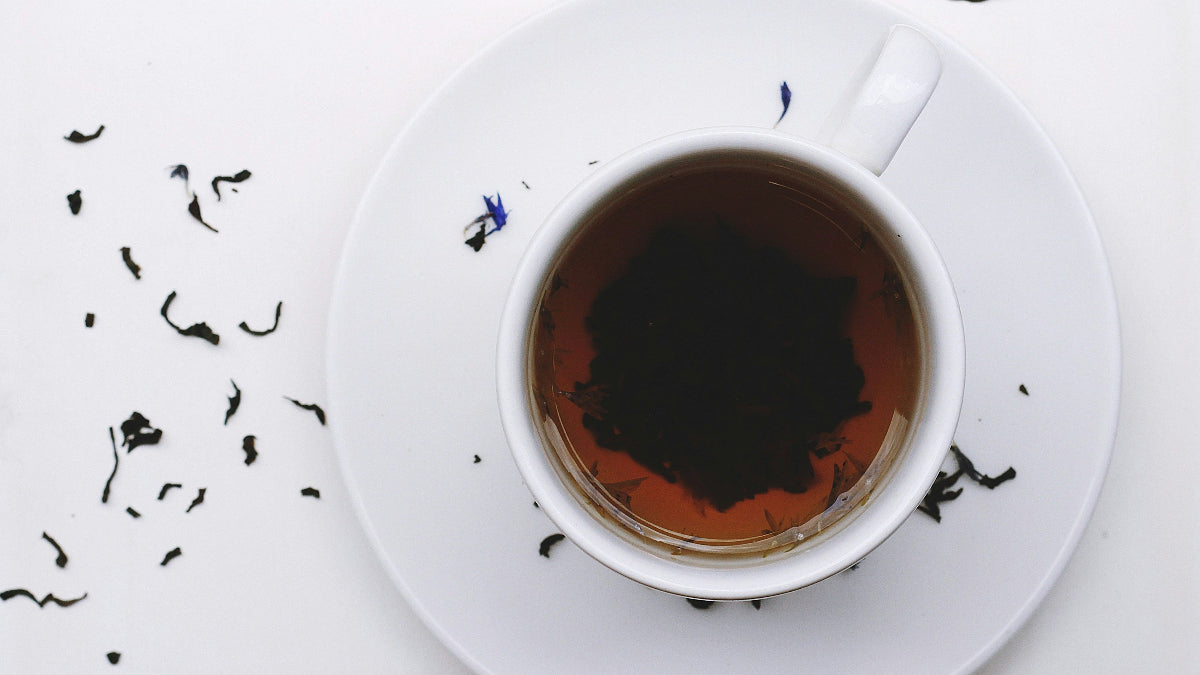 Tea cup with saucer on a white background with scattered tea leaves